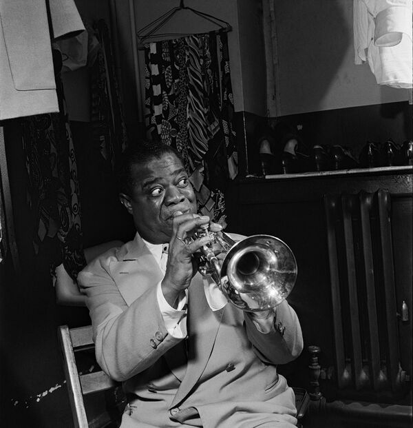 American jazzman Louis Armstrong plays the trumpet in his dressing room before a show in 1947 in a New York jazz cabaret.Armstrong is one of the most influential figures in jazz. With his instantly recognizable rich, gravelly voice, Armstrong was a talented singer, musician and skillful improviser. His career spanned five decades and several eras in jazz history. - Sputnik International