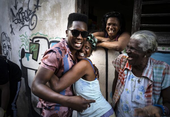 Cuban singer Cimafunk hugs a woman during the music conga through the streets of Old Havana at the 35th Cuban Jazz Plaza festival.Cimafunk is famous for mixing funk and hip-hop with Afro-Caribbean music. - Sputnik International