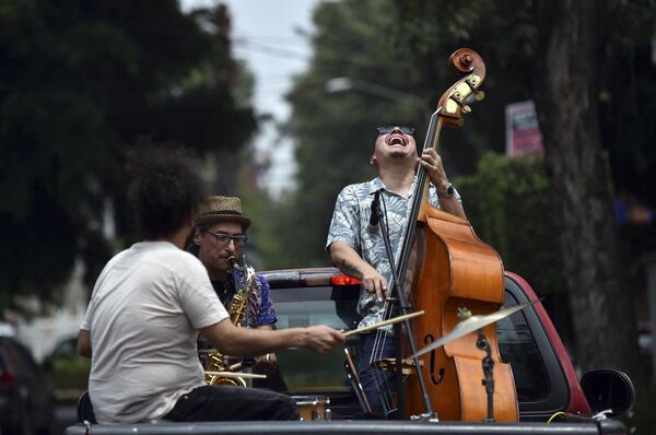The Maroto Jazz Trio band, made up of Diego Maroto on the saxophone, Jorge Molina on double bass and Edy Vega on drums, perform atop a van through neighborhoods in Mexico City.  The group performed amidst the coronavirus pandemic to support the stressed population.  - Sputnik International