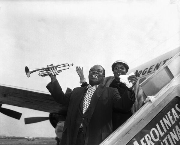 Louis Armstrong, accompanied by his wife, prepares to take off from Idlewild Airport, New York, in 1957, for a concert tour of five South American countries.   - Sputnik International