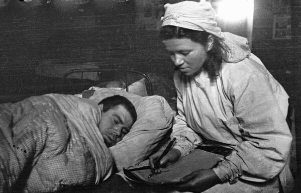 The sister of a medical battalion on the 1st Baltic Front helps a wounded soldier write a letter to his relatives. - Sputnik International