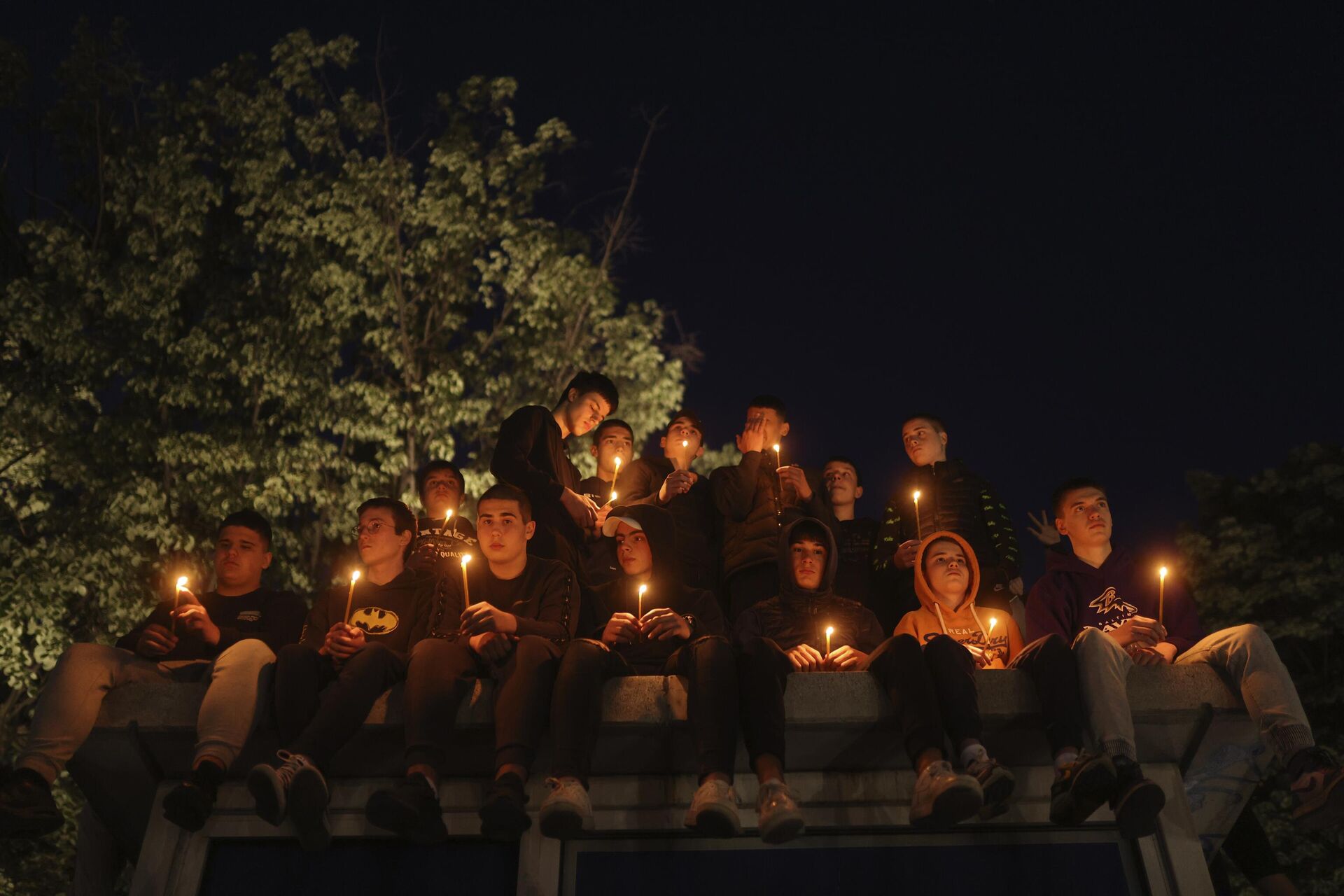 People hold candles for the victims near the Vladislav Ribnikar school in Belgrade, Serbia, Wednesday, May 3, 2023. Police say a 13-year-old who opened fire at his school drew sketches of classrooms and made a list of people he intended to target. He killed eight fellow students and a school guard before being arrested. - Sputnik International, 1920, 03.05.2023