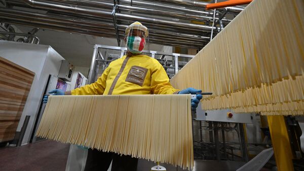 Co-owner with his three brothers and production manager of the Pasta di Gragnano factory near Naples, Antonino Moccia, wearing a face mask in the colors of the Italian flag, processes tagliatelle pasta at the production line on April 24, 2020. - Sputnik International
