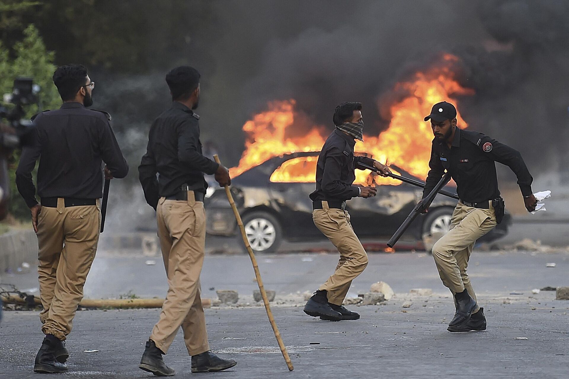 Policemen retreat after firing teargas shells towards Pakistan Tehreek-e-Insaf (PTI) party activists and supporters of former Pakistan's Prime Minister Imran near burning car during a protest against the arrest of their leader in Karachi on May 9, 2023 - Sputnik International, 1920, 11.05.2023