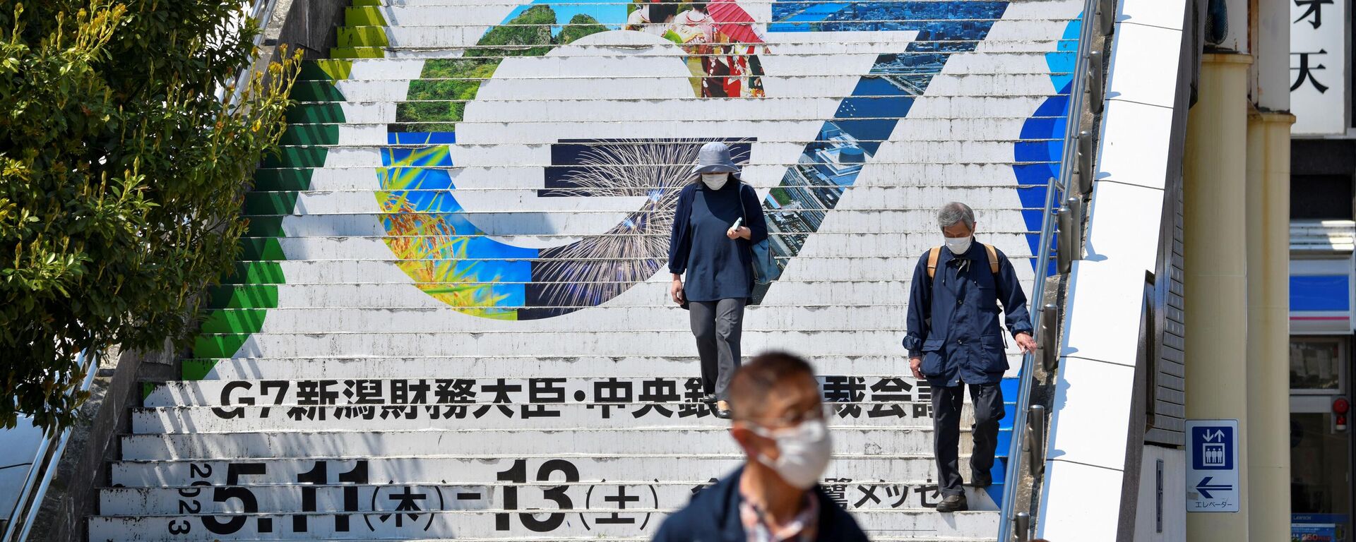 La gente baja las escaleras mostrando el logotipo de la próxima reunión de ministros de finanzas y gobernadores de bancos centrales del G7 en la estación de tren de Niigata el 10 de mayo de 2023 (Sputnik International, 1920, 22.05.2023)