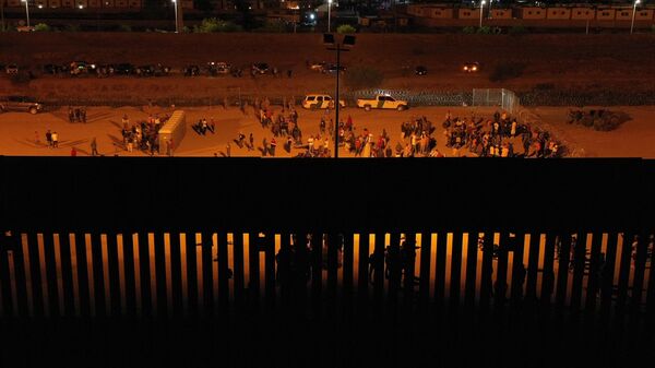 Migrants wait at night along the border wall to surrender to US Customs and Border Protection (CBP) Border Patrol agents for immigration and asylum claim processing before the expiration of Title 42.  - Sputnik International
