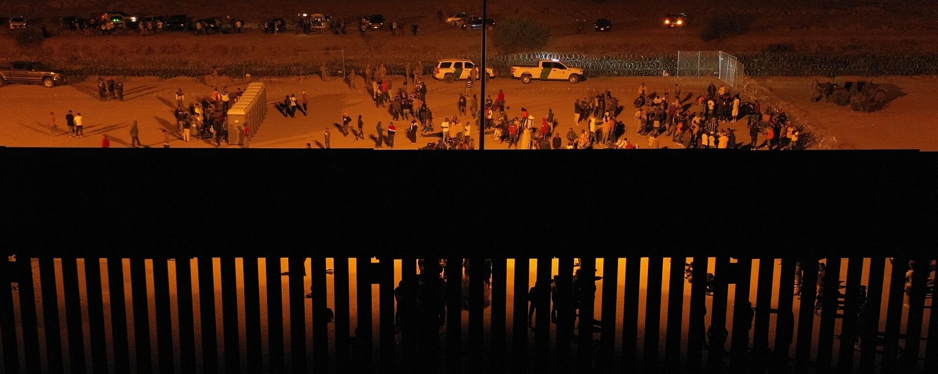 Migrants wait at night along the border wall to surrender to US Customs and Border Protection (CBP) Border Patrol agents for immigration and asylum claim processing before the expiration of Title 42.  - Sputnik International, 1920, 12.05.2023
