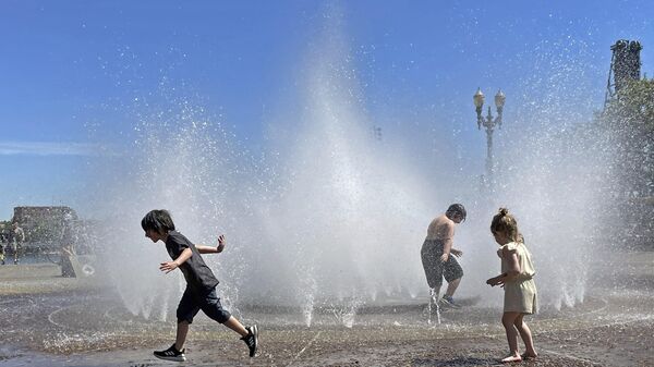 Children play in a fountain to cool off in downtown Portland, Ore., Friday, May 12, 2023. An early May heat wave this weekend could surpass daily records in parts of the Pacific Northwest and worsen wildfires already burning in western Canada, a historically temperate region that has grappled with scorching summer temperatures and unprecedented wildfires fueled by climate change in recent years.  - Sputnik International