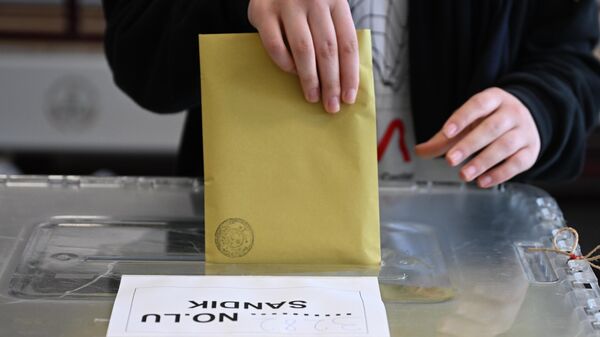 A voter drops the ballots into the ballot box at the polling station during the presidential and parliamentary elections - Sputnik International