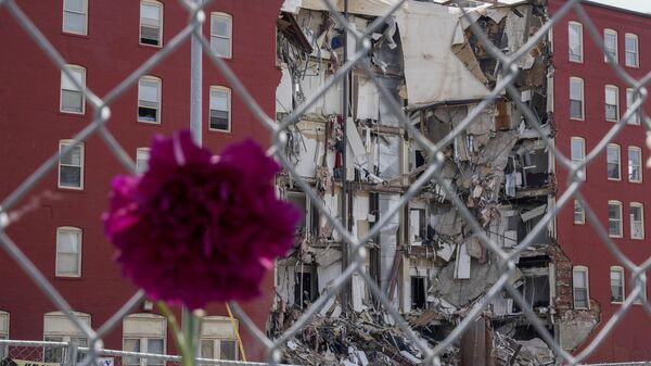A flower hangs from a fence at the where on Sunday an apartment building partially collapsed in Davenport, Iowa, Wednesday, May 31, 2023. Five residents of a six-story apartment building that partially collapsed in eastern Iowa remained unaccounted for Tuesday, and authorities feared at least two of them might be stuck inside rubble that was too dangerous to search.  - Sputnik International