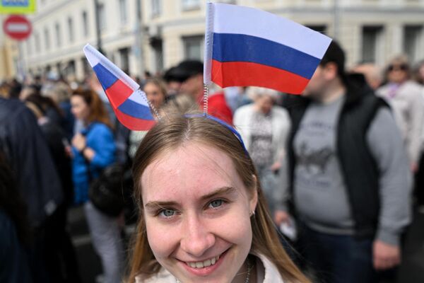 A woman wears Russian national flags as she arrives at the patriotic concert at the Red Square in downtown Moscow ahead the Russia Day on June 11, 2023. - Sputnik International