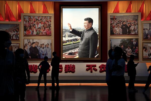 People stand in front of images of Chinese President Xi Jinping at the Museum of the Communist Party of China in Beijing. - Sputnik International