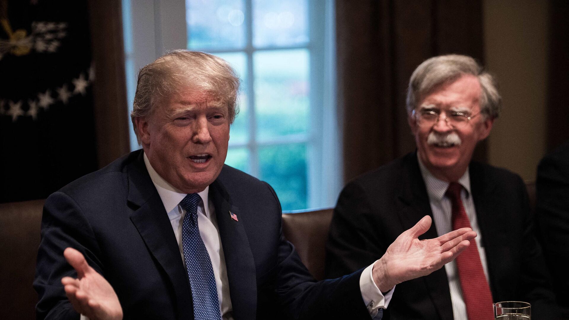 US President Donald Trump speaks during a meeting with senior military leaders at the White House in Washington, DC, on April 9, 2018. At right is new National Security Advisor John Bolton. (Photo by NICHOLAS KAMM / AFP) - Sputnik International, 1920, 27.06.2023