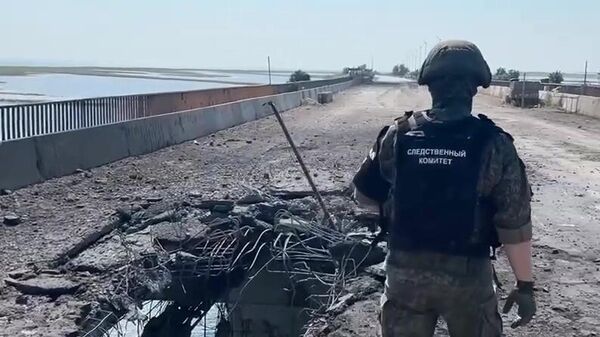 In this video grab a Russian Investigative Committee serviceman stands on a bridge damaged during the Ukrainian armed forces' attack, on the administrative border between the Kherson Region and the Crimea near the village of Chongar, Crimea, Russia. - Sputnik International