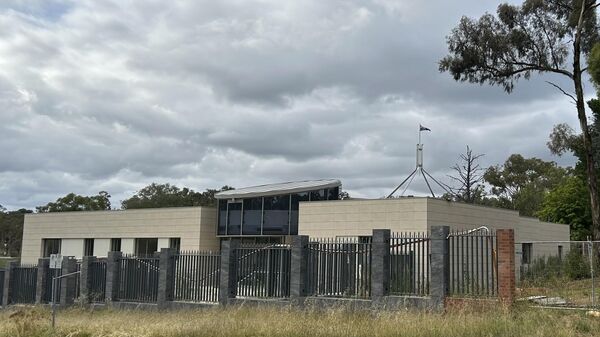 The Australian flag flies on Parliament House, seen behind an unoccupied building on the grounds of a proposed new Russian embassy near the Australian Parliament in Canberra - Sputnik International