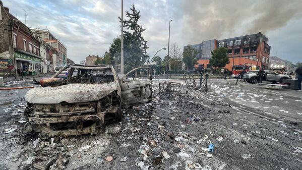 A burnt out vehicle stands on a street in front of the fire-damaged Tessi group building in the Alma district of Roubaix.  - Sputnik International