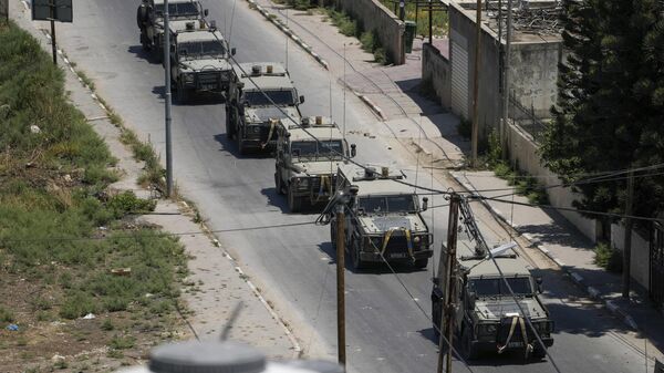 A convoy of army vehicles is seen during an Israeli military raid on the militant stronghold of the Jenin refugee camp in the occupied West Bank, Monday, July 3, 2023. Israeli drones struck targets and deployed hundreds of troops in the area in the largest operation in the area in more than a year of fighting. Palestinian health officials said at least eight Palestinians were killed. - Sputnik International