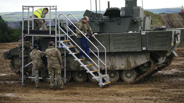 Britain's Defence Secretary Ben Wallace uses steps to climb down from a tank during a visit the Bovington Camp, a British Army military base where Ukrainian soldiers are training on Challenger 2 tanks, in Dorset, England - Sputnik International
