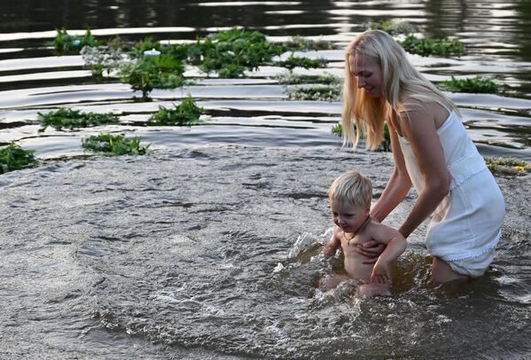 The holiday is also associated with love and romance, and young couples often go into the forest to look for the mythical fern flower, which is said to bring luck in love.Above: a participant in Kupala Night bathes a baby in the river in the park in Zelenodolsk. - Sputnik International