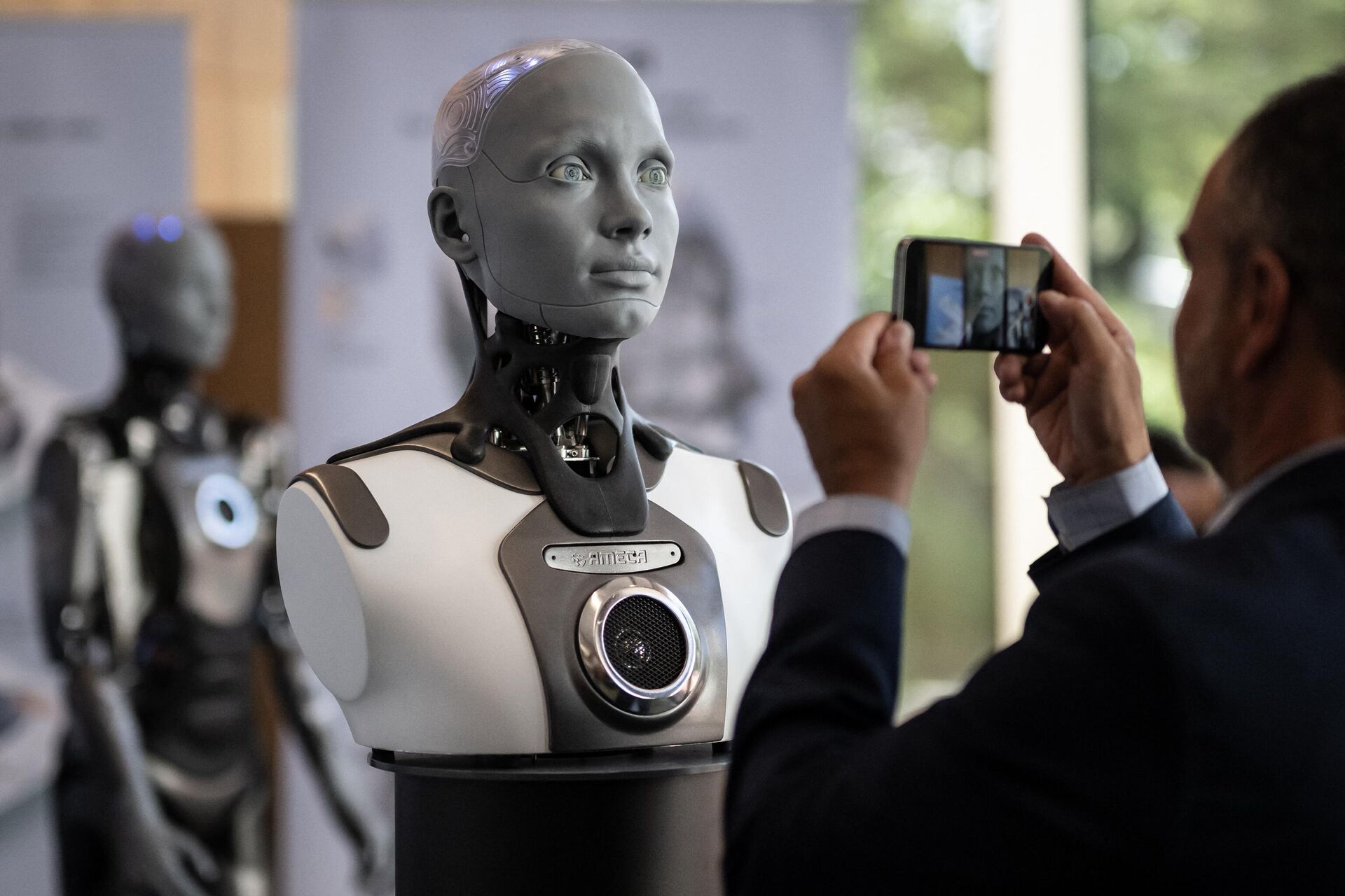 A visitor takes a picture of humanoid AI robot Ameca at the booth of Engineered Arts company during the world's largest gathering of humanoid AI Robots as part of International Telecommunication Union (ITU) AI for Good Global Summit in Geneva, on July 5, 2023.  - Sputnik International, 1920, 08.07.2023