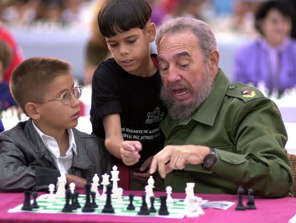 Cuban President Fidel Castro, on the right, talks to Eriberto Diaz, in the middle, national chess champion in the 11-12 age range, and Lazaro Castro while playing chess during a tournament at the Plaza de la Revolucion in Havana, Cuba on Saturday, December 7, 2002.  - Sputnik International