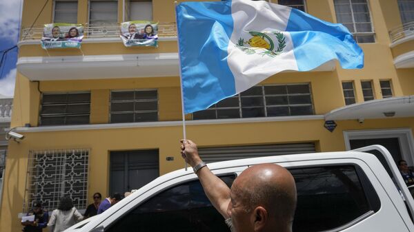 A supporter of the Seed Movement political party waves a national flag during a raid of the party headquarters, in Guatemala City, Friday, July 21, 2023. Guatemalan agents and police raided the offices of Seed Movement presidential candidate Bernardo Arevalo as part of an investigation into alleged wrongdoing in the party's formation. - Sputnik International