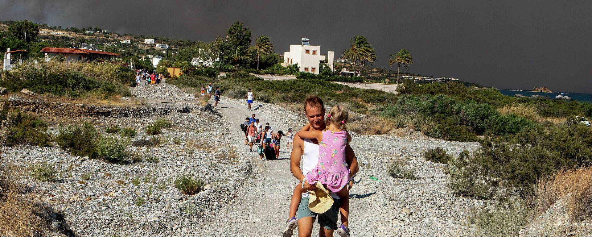 A man carries a child as they leave an area where a forest fire burns, on the island of Rhodes, Greece, Saturday, July 22, 2023.  - Sputnik International, 1920, 26.07.2023