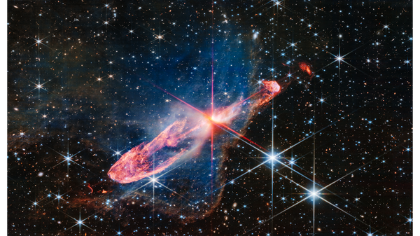 NASA’s James Webb Space Telescope has captured a tightly bound pair of actively forming stars, known as Herbig-Haro 46/47, in high-resolution near-infrared light. Look for them at the center of the red diffraction spikes. The stars are buried deeply, appearing as an orange-white splotch. They are surrounded by a disk of gas and dust that continues to add to their mass. - Sputnik International