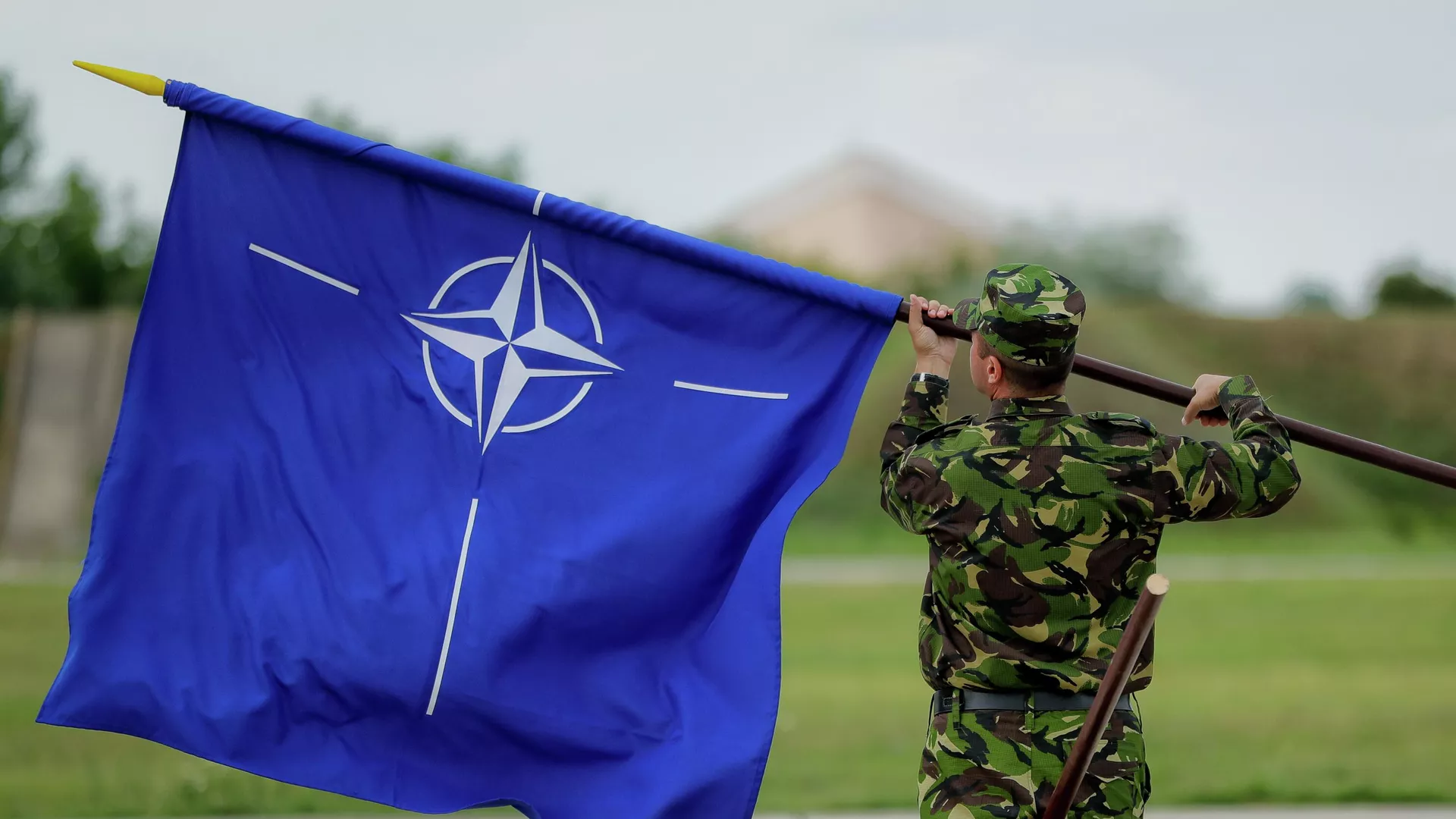 A Romanian serviceman furls the NATO flag. File photo - Sputnik International, 1920, 29.06.2024