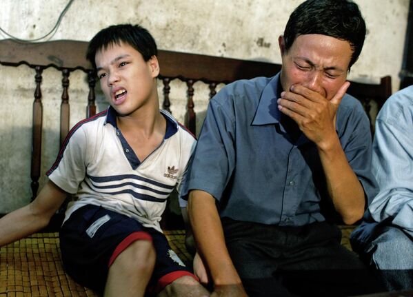 Nguyen Van Quy, 49, weeps while sitting with his son Nguyen Quang Trung, 17, at his house in Hai Phong, Vietnam on July 2004. Quy believes his children&#x27;s birth defects were caused by Agent Orange that he was exposed to during the Vietnam War.  - Sputnik International