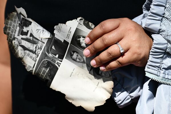 A woman holds a page of a yearbook as she looks for belongings through the ashes of their family’s home, destroyed by the devastating Hawaii wildfires. - Sputnik International