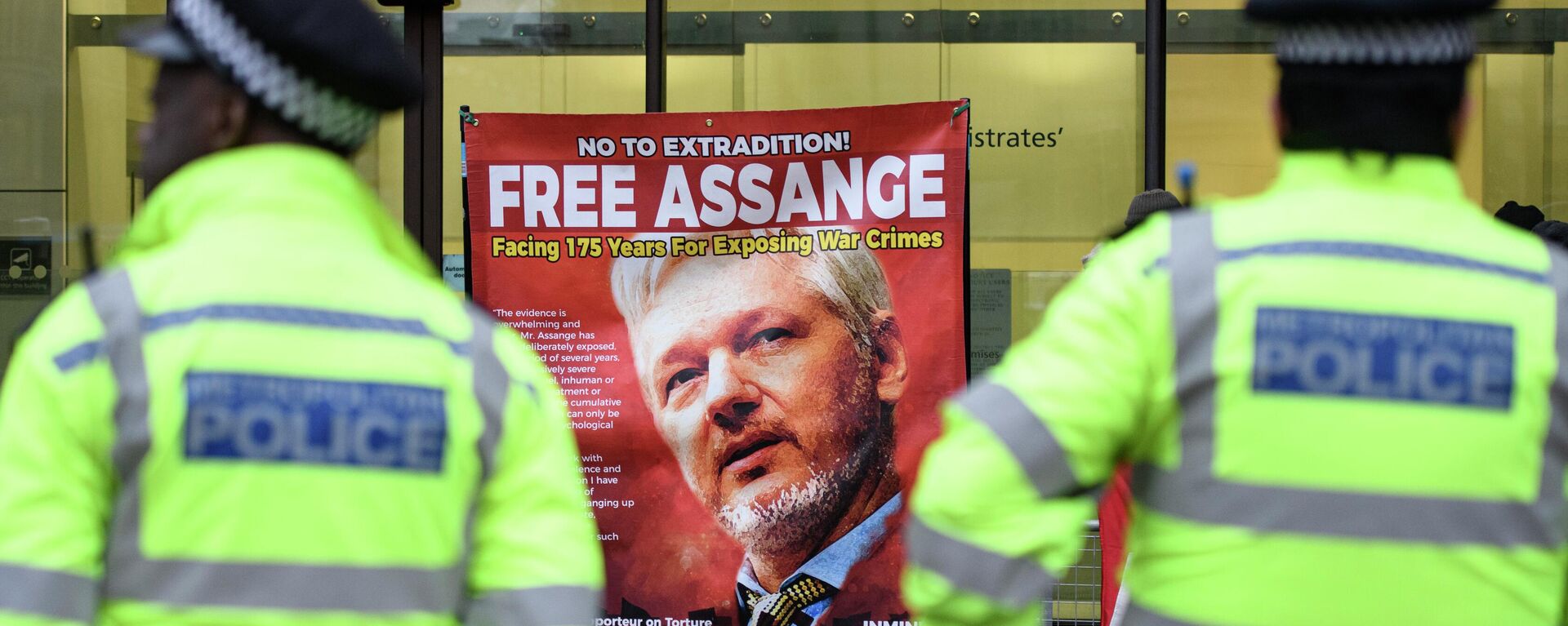 A police officer stands in front of the banner with a photo of Julian Assange near the Westminster Magistrates' Court in London - Sputnik International, 1920, 10.11.2023