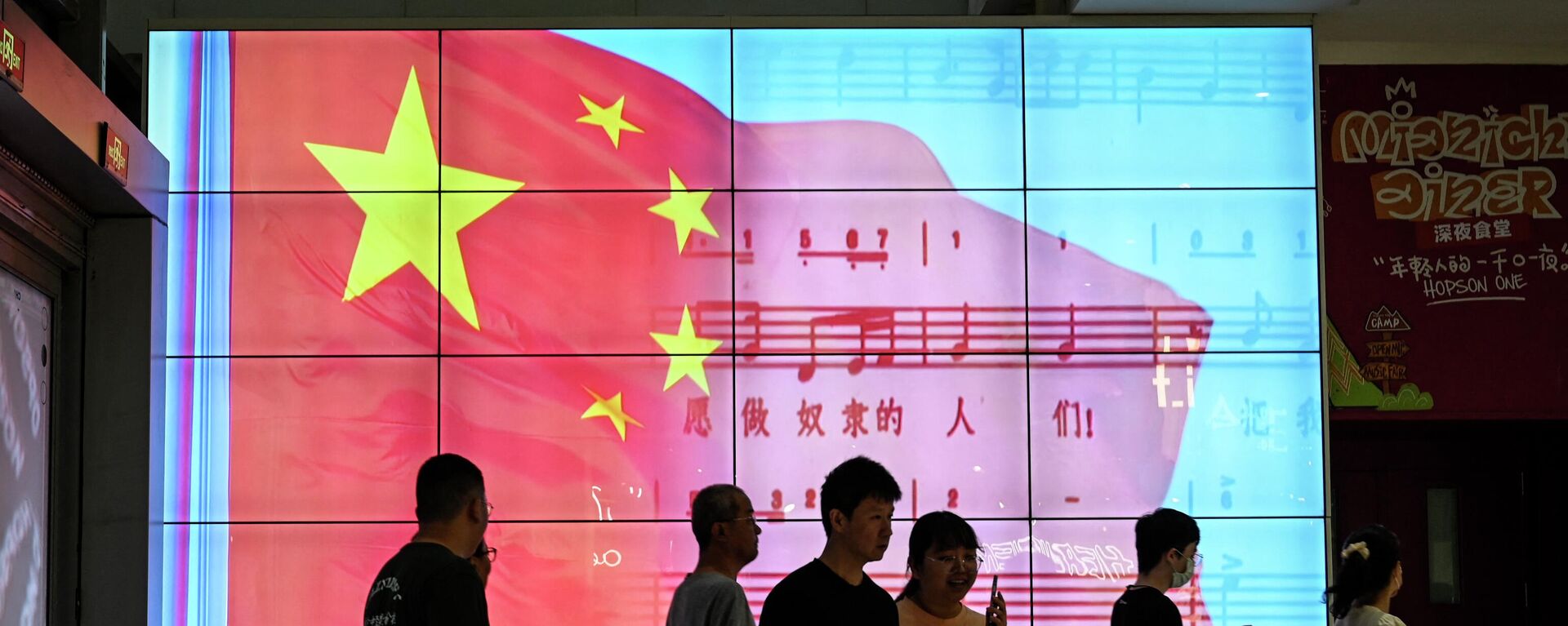 People walk past a screen showing a Chinese national flag at a shopping mall in Beijing on May 26, 2023 - Sputnik International, 1920, 14.08.2023