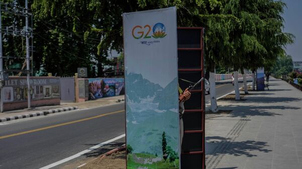 An Indian policeman guards from behind a temporary security post as delegates from the Group of 20 nations  arrive to participate in a tourism meeting in Srinagar, Indian controlled Kashmir, Monday, May 22, 2023.  - Sputnik International