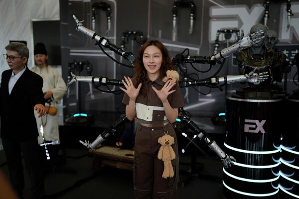 A woman poses in front of a six-armed robot at the annual World Robot Conference at the Beijing Etrong International Exhibition and Convention Center in Beijing. - Sputnik International