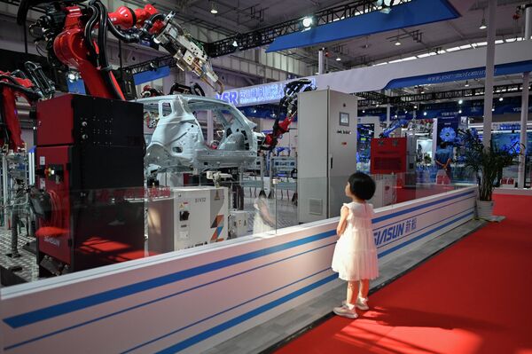A child looks at a Siasun robot arm. - Sputnik International