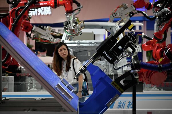 A woman looks at a robot arm at the 2023 World Robot Conference. - Sputnik International