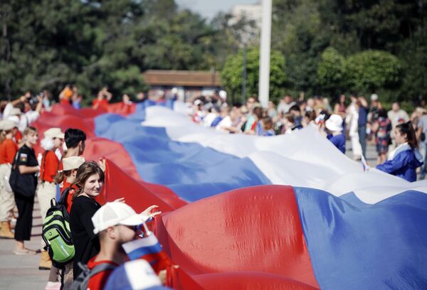 Participants in celebrations marking Russian Flag Day unfurl a 100-metre-long Russian flag on Lenin Square in Mariupol. - Sputnik International