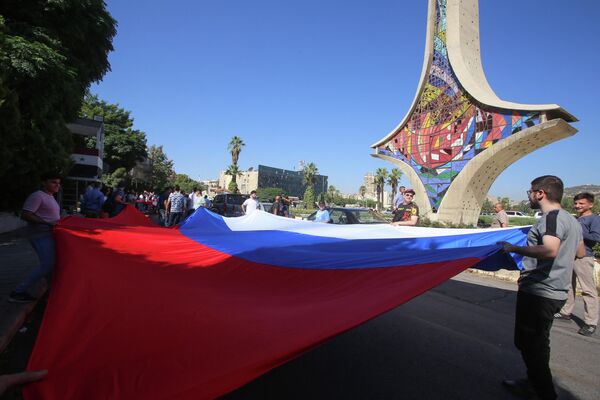 The youth holding a Russian flag at the Umayyads Square in Damascus in celebration of Russia&#x27;s Flag Day, on August 22, 2023. - Sputnik International