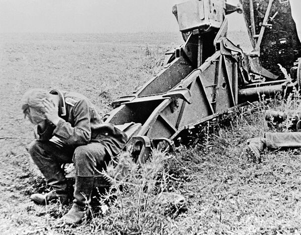 German soldier sits next to a destroyed SIG.33 150mm heavy infantry gun. - Sputnik International