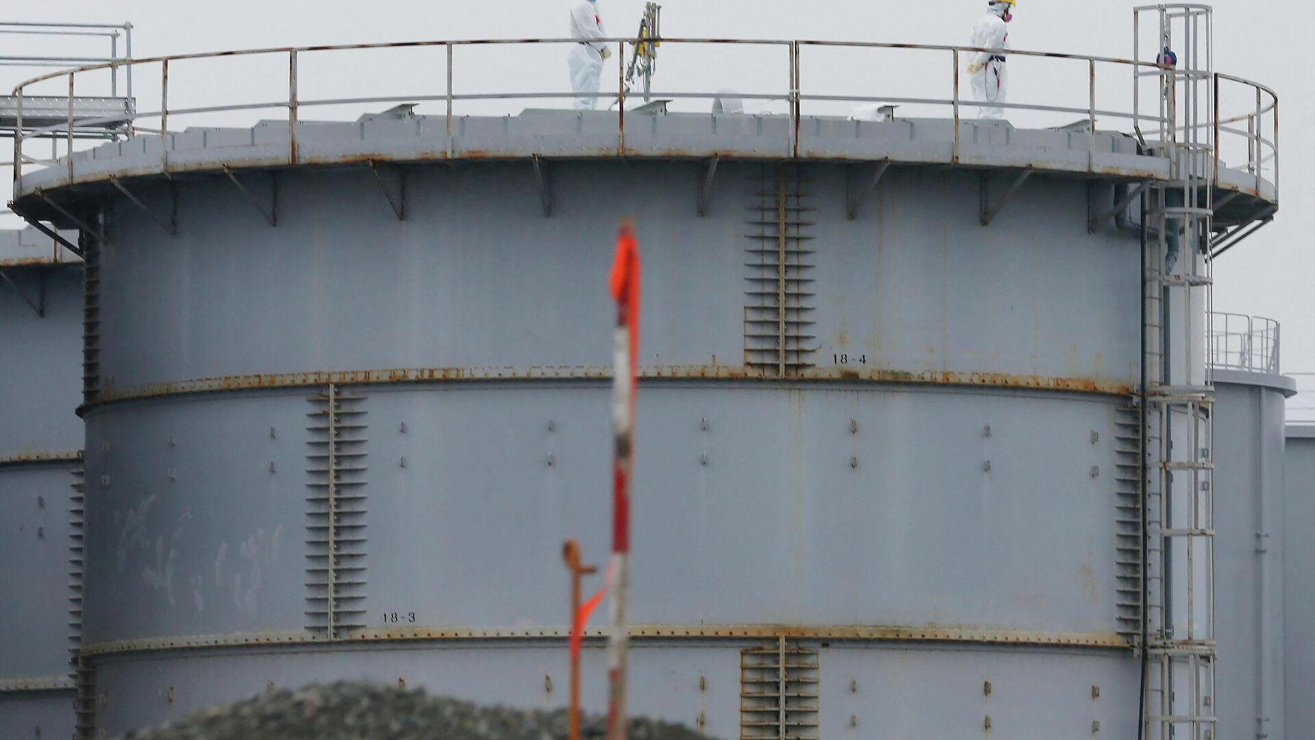 This file photo taken on November 12, 2014 shows workers wearing protective gear standing on a water tank that stores radiation contaminated water at the Fukushima Dai-ichi nuclear power plant in Okuma, Fukushima Prefecture.  - Sputnik International, 1920, 05.09.2023
