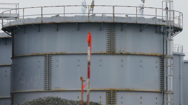 This file photo taken on November 12, 2014 shows workers wearing protective gear standing on a water tank that stores radiation contaminated water at the Fukushima Dai-ichi nuclear power plant in Okuma, Fukushima Prefecture.  - Sputnik International