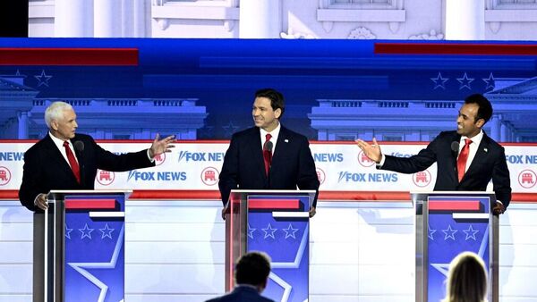 Former US Vice President Mike Pence (L) and entrepreneur and author Vivek Ramaswamy (R) gesture toward Florida Governor Ron DeSantis during the first Republican Presidential primary debate at the Fiserv Forum in Milwaukee, Wisconsin, on August 23, 2023. - Sputnik International