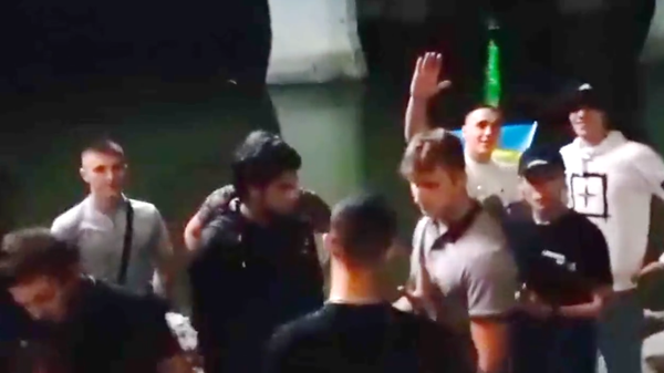 Group of young Ukrainians confront Poles in Warsaw and attempt to force them to chant Glory to Ukraine. Screenshot of viral video. - Sputnik International