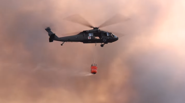 A Louisiana Department of Agriculture and Forestry helicopter prepares to drop water on one of more than 450 wildfires raging in the state on August 29, 2023. - Sputnik International