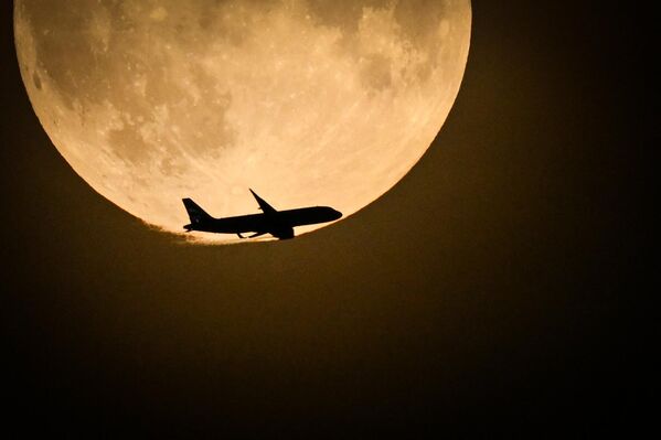 A British Airways Airbus A320 from Belfast preparing to land at Heathrow flies past the full Moon rising in the sky of London, Wednesday, Aug. 30, 2023. - Sputnik International