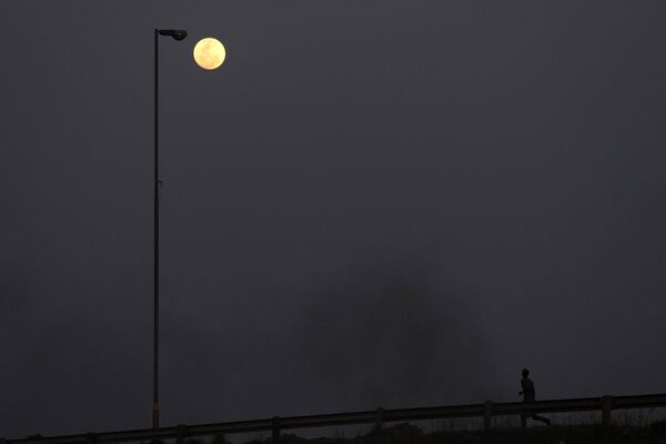 The Supermoon is seen on the sky as a man runs on the street, in Vosloorus, east of Johannesburg, South Africa, Wednesday, Aug. 30, 2023. - Sputnik International