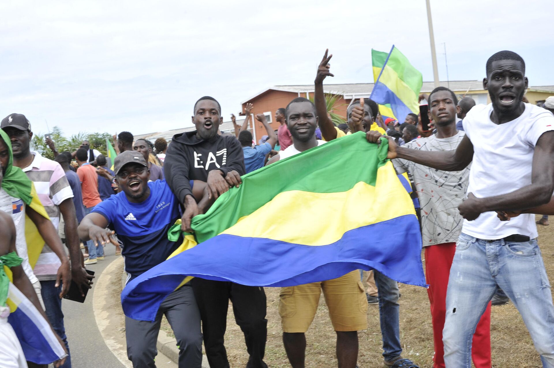 Residents gesture and hold a Gabon national flag in Libreville on August 30, 2023 - Sputnik International, 1920, 31.08.2023