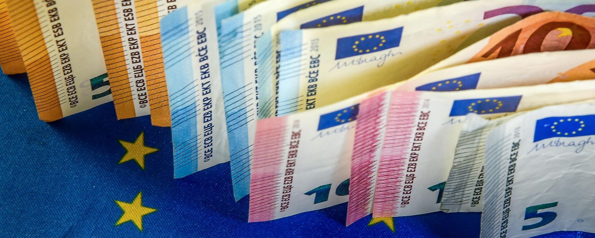 Euro banknotes are displayed next to an European Union flag. - Sputnik International, 1920, 01.09.2023