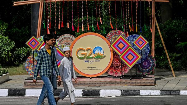 Pedestrians walk next to a G20 India summit logo ahead of its commencement in New Delhi on September 3, 2023.  - Sputnik International